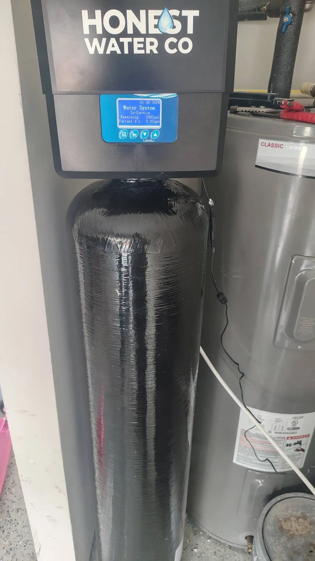 Honest Water Co branded whole-home water softener with digital display installed next to a water heater in a North Georgia garage