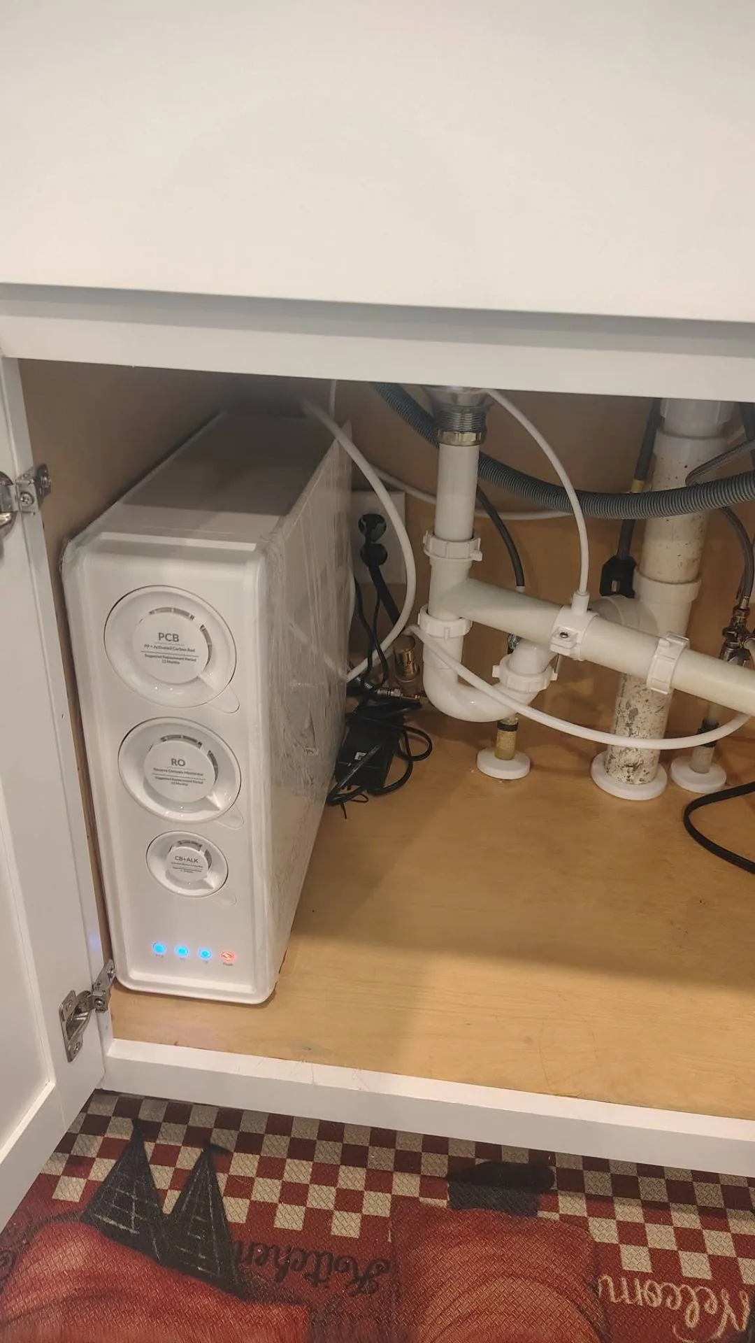 Tankless reverse osmosis drinking water system with PCB, RO, and CB+ALK filter stages mounted under a kitchen sink