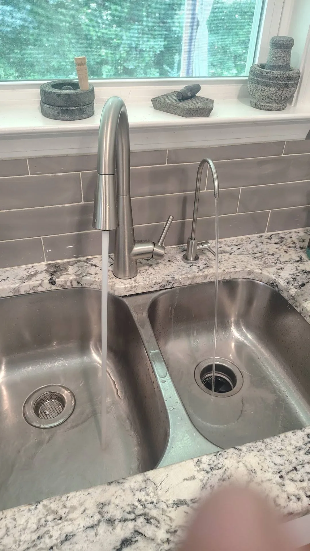 Brushed nickel dedicated reverse osmosis drinking water faucet flowing alongside the main kitchen faucet on a granite countertop