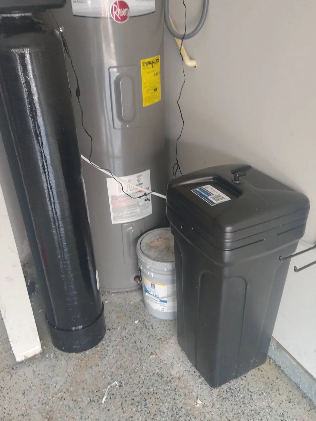Whole-home water softener tank, brine tank, and water heater installed in a clean North Georgia garage utility corner