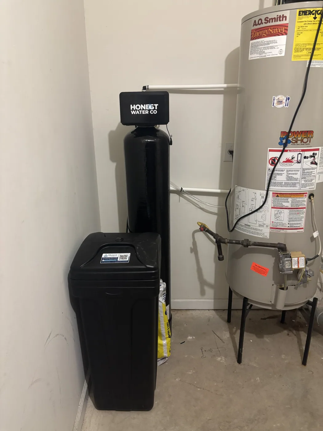 Installed whole-home water treatment tank and brine tank beside a water heater
